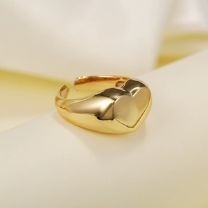 Detailed macro view of a minimalist gold heart signet ring on a soft cream fabric