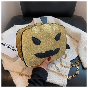 Close-up of glitter pumpkin crossbody bag with gold chain strap and jack-o-lantern face