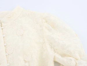 Détail de dentelle florale élégante avec boutons en perles et manches bouffantes