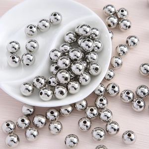 Macro shot of silver round acrylic spacer beads on a ceramic tray for DIY jewelry