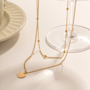 Detail of double-layer 18K gold stainless steel chain with round pendant and beads