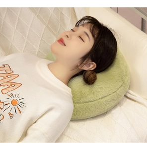 Detailed view of a soft green plush tennis ball pillow used as a cozy headrest