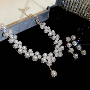 Elegant floral pearl necklace and earring set with shimmering crystals on black surface