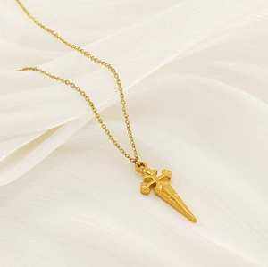 Macro detail of a vintage gold cross pendant lying on soft silk fabric texture