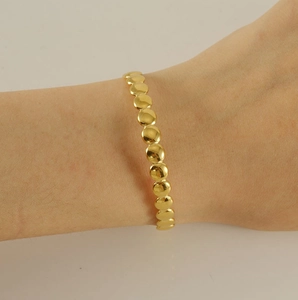 Detailed view of adjustable 18K gold-plated bangle featuring flat circular coin links on wrist