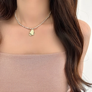 Close-up of gold irregular pendant with silver faceted bead chain on woman's neck