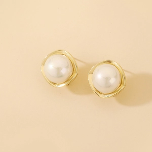 Detail of elegant gold earrings with irregular wave edges and large white round pearls