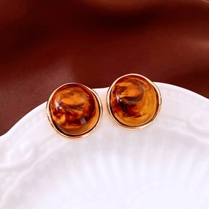 Detailed close-up of amber round earrings on a white tray with silk background