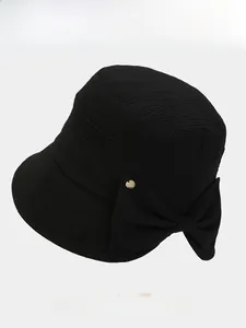 Detailed texture of black fisherman hat featuring a bowknot and a gold button accent