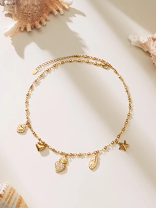 Detail of 18k gold plated beaded necklace with heart, crown, and coin charms on white background