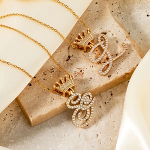 Exquisite gold-plated crown initial necklace with cubic zirconia on marble background