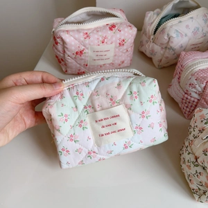 Detail of pink floral quilted makeup bag with soft fabric texture and zipper closure