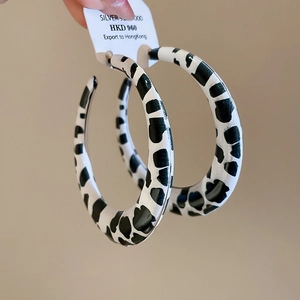 Close-up of black and white cow print hoop earrings with 925 silver needles