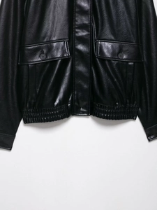 Detail view of black faux leather bomber jacket showing elastic hem and flap pocket texture