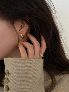 Chic gold-plated hoop earrings and stacked metal rings styled for a trendy minimalist look