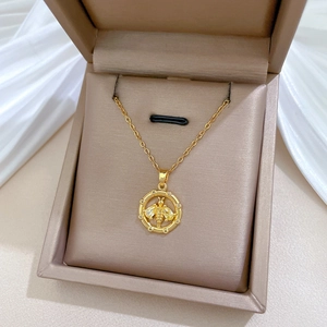 Macro detail of gold bee pendant necklace with yellow gems in a brown jewelry box