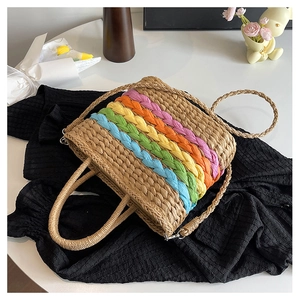 Detail of colorful rainbow stripe weaving on a brown straw tote bag with shoulder strap