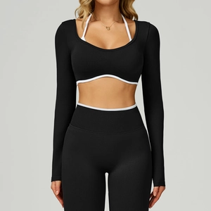 Detail of black long-sleeve yoga crop top featuring white halter neck strap and curved hem