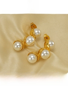Macro shot of S-curve gold plated titanium steel earrings with three white pearls