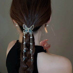 Close-up of butterfly hair claw clip with faux pearls and long tassels on styled hair