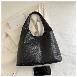 Detail shot of black woven leather texture on a high-capacity minimalist hobo bag
