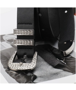 Close-up of black leather belt with rhinestone-studded buckle on a fashion magazine