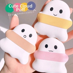 Three ghost-shaped makeup sponges in white with colorful straps held in hand