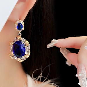 Close-up of vintage oval blue zircon earring with gold finish on a female model
