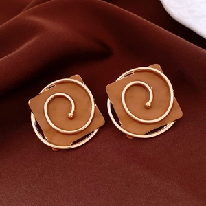 Detailed view of caramel square stud earrings with golden spiral on velvet background