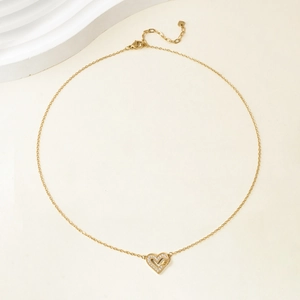Detail of elegant gold heart pendant with sparkling zircons on a delicate chain necklace