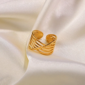 Macro detail of 18K gold multilayer interlocking ring on elegant white satin fabric