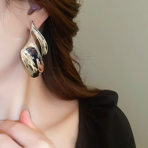 Close-up of polished gold irregular twisted metal earrings on model for a trendy look