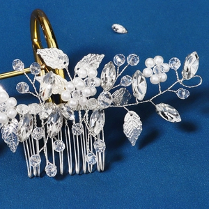 Close-up of silver hair comb with sparkling crystals and white pearls on blue background