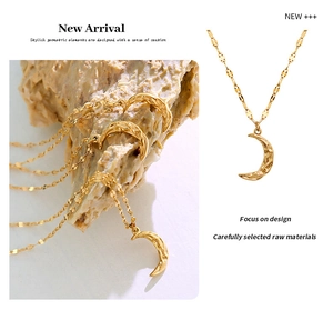 Macro detail of hammered 18K gold crescent moon pendant on a delicate link chain necklace