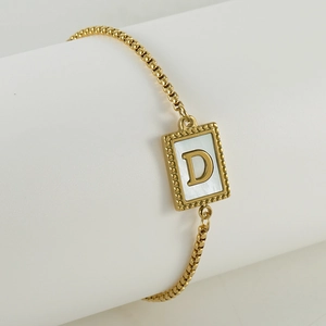 Detail of gold box chain bracelet with white shell inlay square pendant and letter D