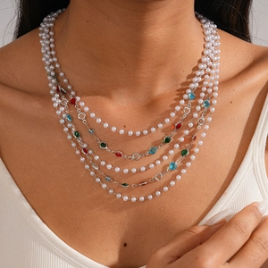 Detail of layered baroque pearl necklace featuring colorful gemstones and silver chains