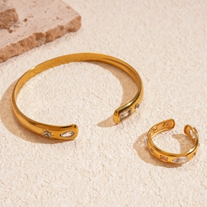 Golden sunburst relief bangle and ring set with white zircons on a natural stone base