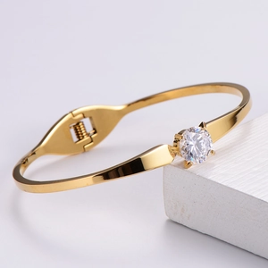 Macro view of polished gold-plated bangle featuring a large sparkling white zircon inlay