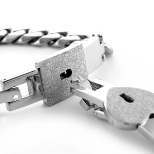 Macro shot of silver Cuban link bracelet with glitter lock and heart key details