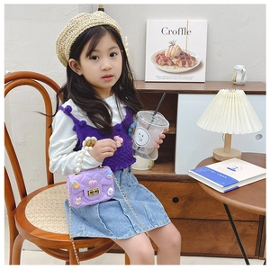 Girl holding purple quilted crossbody bag with pearl handle and cartoon charms
