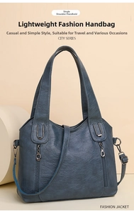 Detail view of large grey-blue faux leather tote bag with vintage texture and metal zippers