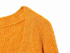 Macro detail of high-quality orange knitted sweater collar and coarse texture