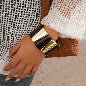 Close-up of a wide geometric acrylic and gold metal link bracelet on a woman's wrist