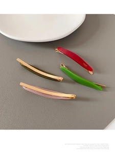 Detail of four acetate hair clips in red, green and pink with metallic creation letters
