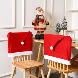 Festive red Christmas hat chair covers with white pompoms on a wooden dining table