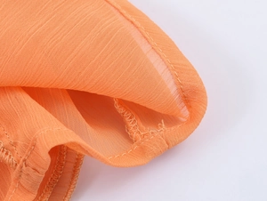 Detailed view of breathable orange layered fabric texture with high-quality edge stitching
