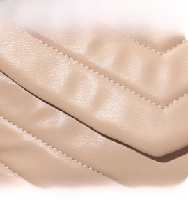 Close-up detail of V-quilted stitching on soft nude pink leather crossbody bag texture