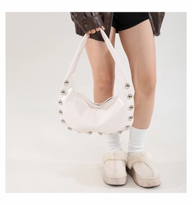 White crescent underarm bag with silver studs on oil wax leather shown on a model