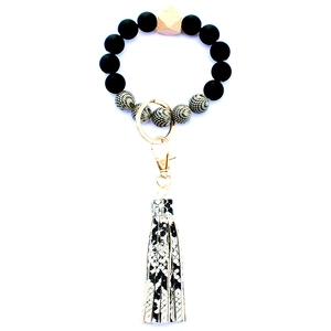 Close-up of beaded keychain featuring black matte beads, wood accents, and snakeskin tassel