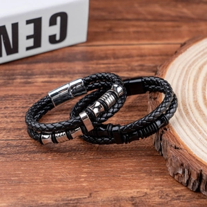 Detail of black braided leather bracelets with magnetic clasps on a rustic wood background